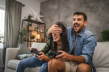 Yetişkin çiftler joystick 'te video oyunu oynarken eğleniyorlar.