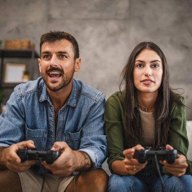 Yetişkin çiftler joystick 'te video oyunu oynarken eğleniyorlar.