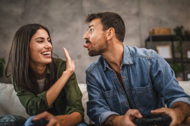 Yetişkin çiftler joystick 'te video oyunu oynarken eğleniyorlar.