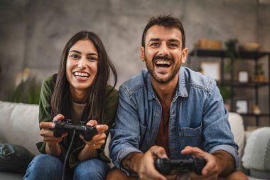Yetişkin çiftler joystick 'te video oyunu oynarken eğleniyorlar.