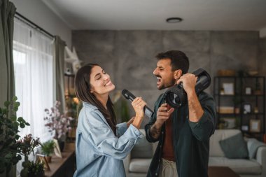 Çiftler evde karaoke partisi veriyorlar mikrofonda şarkı söylüyorlar, hoparlörle dans ediyorlar.