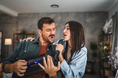 Çiftler evde karaoke partisi veriyorlar mikrofonda şarkı söylüyorlar, hoparlörle dans ediyorlar.