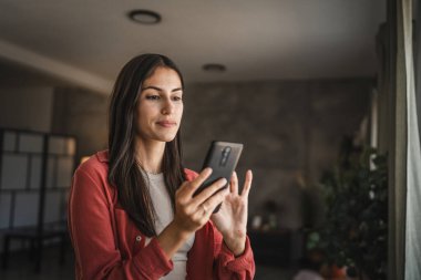 Yetişkin bir genç kadının portresi. Bekleyin ve cep telefonu kullanın.
