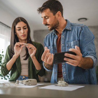 Çift cep telefonundan kil heykel ve çömlek yapmayı öğreniyor.