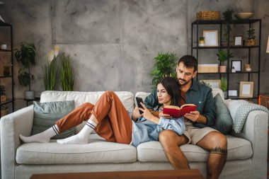 Erkek arkadaşı kitap okuyor ve kız arkadaşına sarılıyor.