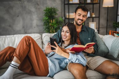 Erkek arkadaşı kitap okuyor ve kız arkadaşına sarılıyor.