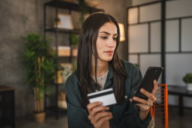 Yetişkin kadınlar evlerinde cep telefonlarıyla internet üzerinden alışveriş yaparlar.