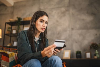 Yetişkin kadınlar evlerinde cep telefonlarıyla internet üzerinden alışveriş yaparlar.