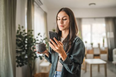 Yetişkin bir genç kadının portresi. Bardağı tut ve cep telefonu kullan.