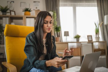 Yetişkin kadın evde çalışıyor. Ara ver ve cep telefonu kullan.