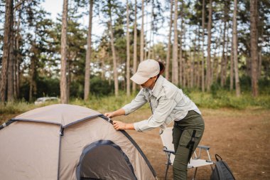 Genç bayan ormanda kamp yapmak için doğada bir çadır kurdu.