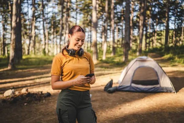 Kulaklıklı genç bir kadının portresi çadırın önünde duruyor. Cep telefonu kullan.