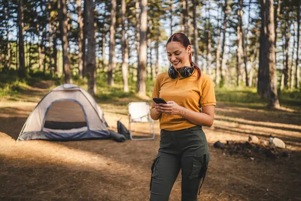 Kulaklıklı genç bir kadının portresi çadırın önünde duruyor. Cep telefonu kullan.