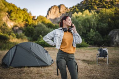 Kulaklık takan ve cep telefonuyla konuşan genç bir kadının portresi