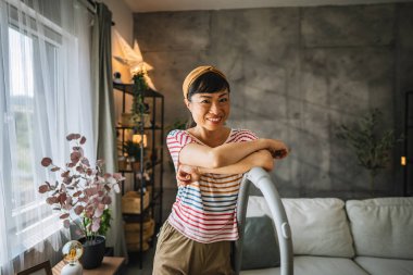 Olgun Japon kadın portresi gülümse ve elektrikli süpürgeyle ayakta dur.