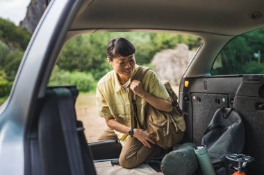 Olgun Japon kadın arabasının arkasında kamp yapmak için bir şeyler alıyor.