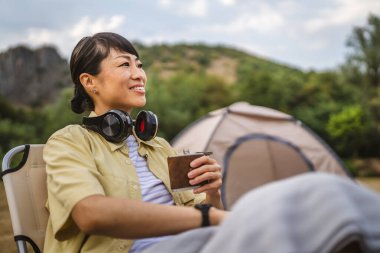 Olgun Japon kadın alkol şişesiyle kamp gezisinde dinleniyor.