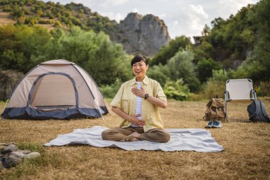 Olgun Japon kadın ön çadırdaki dağda meditasyon yapıyor.