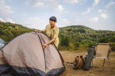 Olgun Japon kadın ormanda kamp yapmak için doğada bir çadır kurdu.