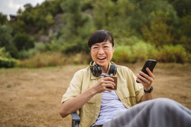 Kamp gezisinde cep telefonu ve alkollü olgun Japon kadın.