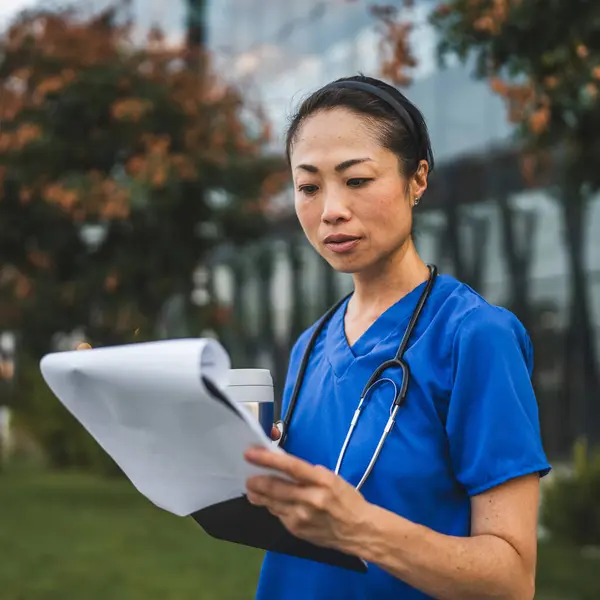 stock image mature japanese doctor stand in front the building and hold clipboard