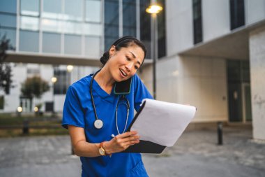 Mutlu Japon kadın doktor cep telefonuyla konuşur ve panoyu tutar.