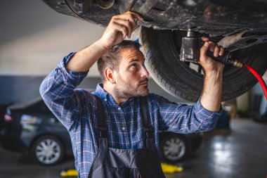 Araba tamircisi güçlü bir araç kullanır. Otomobil iniş sistemini tamir eder, tamir eder.