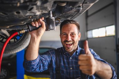 Araba tamircisinin portresi bir araç tut ve otomobilin altında dur