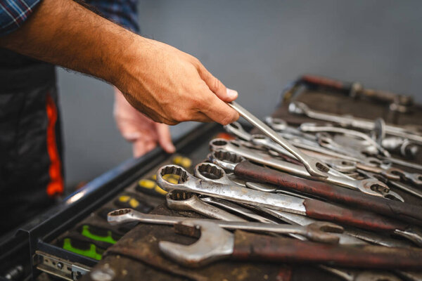 Unknown car mechanic in a workshop organize various wrenches, screwdrivers, and other tools neatly in a toolbox drawer, preparing for a repair or maintenance task