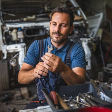 Araba tamircisi arka planda açık motorlu temiz giysiler tutuyor.