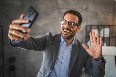 İş adamı, video görüşmesi sırasında cep telefonundan selamlama gönderdi.