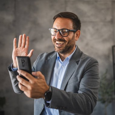İş adamı, video görüşmesi sırasında cep telefonundan selamlama gönderdi.