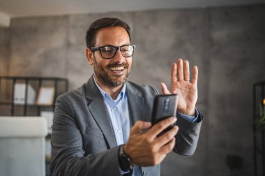 İş adamı, video görüşmesi sırasında cep telefonundan selamlama gönderdi.