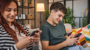 Genç çift koltuğa oturur ve cep telefonu kullanır. Telefon bağımlılığının gerçekçi bir fotoğrafı.