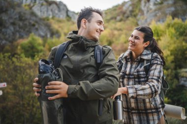 Kız arkadaşı erkek arkadaşına sırt çantasını toplaması ve bağlaması için yardım ediyor.