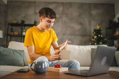 Genç yetişkin bir adam, laptop 'daki video görüşmesi sırasında tebrik kartını okur.