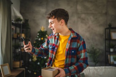 Genç bir adamın cep telefonunda hediye kutusu açık bir video görüşmesi var.