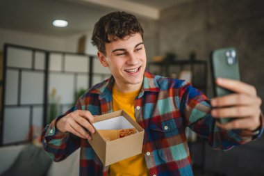 Genç yetişkin erkek cep telefonuyla video görüşmesi sırasında hediye.