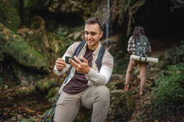 Yetişkin bir gezgin gezgin orman, mağara ve şelale çevresindeki telefon için yol arayabilir ya da cep telefonu kullanabilir.