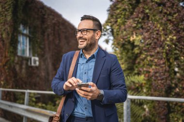 Yetişkin gülüşlü işadamı terasa çık ve cep telefonu kullan.