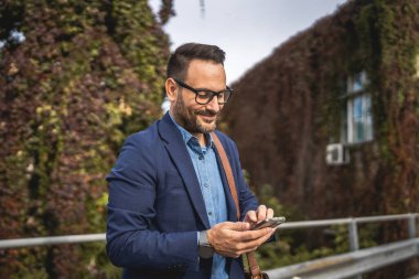 Yetişkin gülüşlü işadamı terasa çık ve cep telefonu kullan.