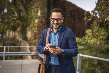 Yetişkin gülüşlü işadamı terasa çık ve cep telefonu kullan.