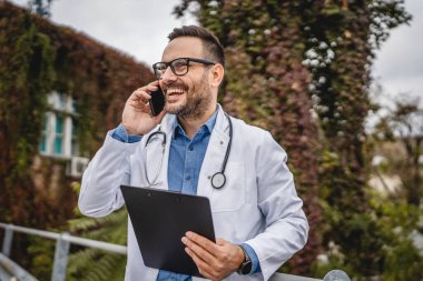 Doktor, panoyu tut ve terasta cep telefonu standında konuş.