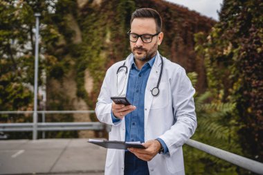 Yetişkin doktor, not panosunu tut ve sonuçların cep telefonuyla fotoğrafını çek.