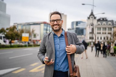 Yetişkin işadamı otobüs durağında cep telefonu kullanıyor