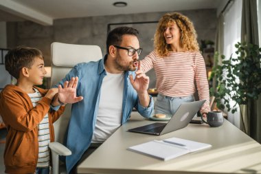 Baba, ailesi dikkatini dağıtırken evden çalışmaya çalışıyor.