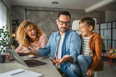 Baba, ailesi dikkatini dağıtırken evden çalışmaya çalışıyor.