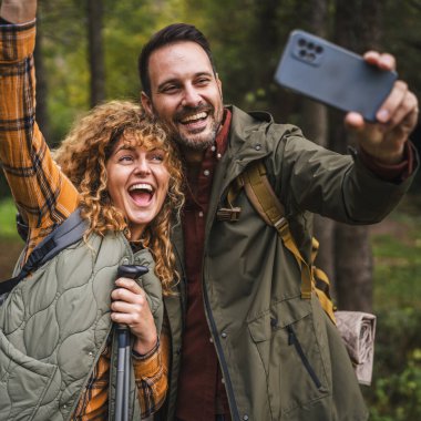 Karı koca yürüyüşçüleri sırt çantasıyla gezerler. Ormanda yürüyüş yaparken kendi portresini ya da video görüntülerini çekerler.