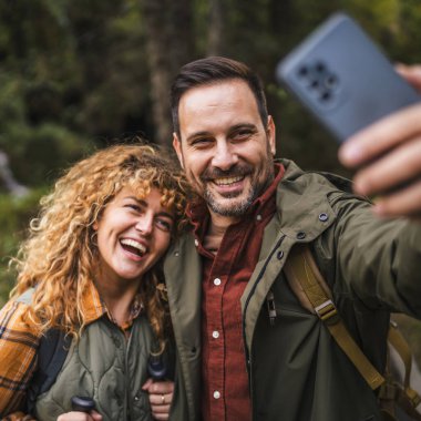 Karı koca yürüyüşçüleri sırt çantasıyla gezerler. Ormanda yürüyüş yaparken kendi portresini ya da video görüntülerini çekerler.