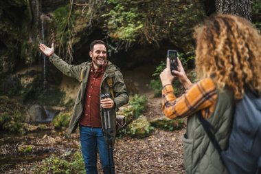 Eşi, sırt çantalı Whit yürüyüş sopalarını ormanda ön mağarada çekerken fotoğrafını çekmiş.